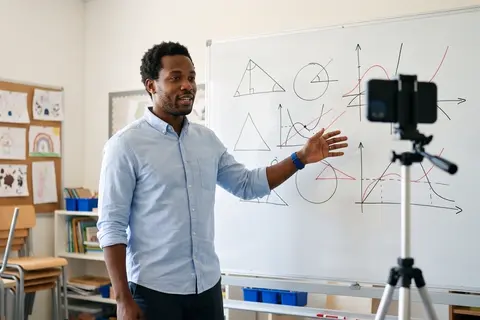 A teacher recording a lesson beside a whiteboard